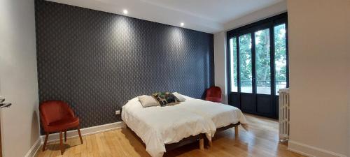 - une chambre avec un lit et deux chaises rouges dans l'établissement Daisy, à Vichy