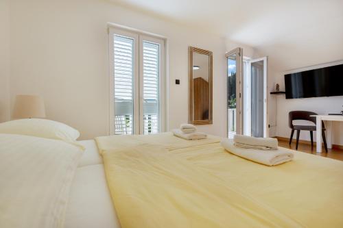 a white bedroom with a large bed with two towels on it at Villa Marina in Slano