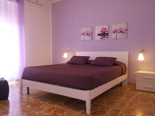 un letto in una stanza con due dipinti sul muro di Appartamento Lorenzo Noto a Noto