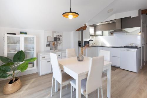 a white kitchen with a white table and white chairs at Torrontero con vistas al mar in Bermeo