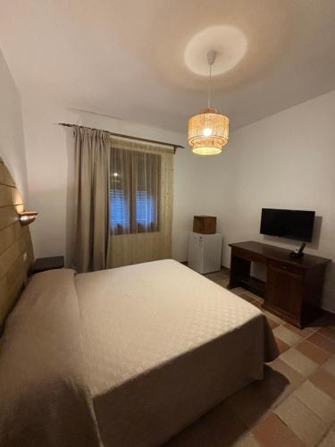 Schlafzimmer mit einem Bett, einem Schreibtisch und einem TV in der Unterkunft B&B Villa Alba in San Vito lo Capo