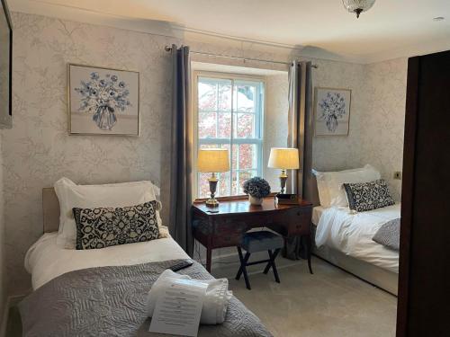 a bedroom with two beds and a desk and a window at Burford Lodge Hotel - Adults only in Burford