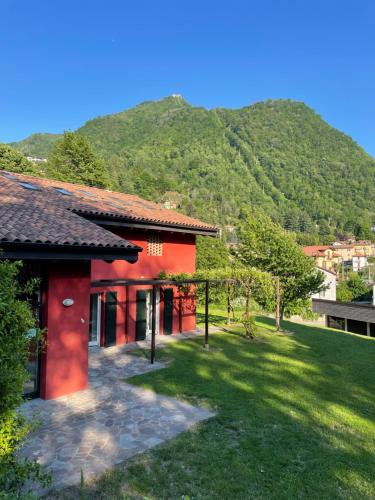 a red house with a mountain in the background at Ostello Casa Rossa in Laveno-Mombello