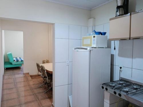 a kitchen with a white refrigerator and a table at Casinha Vó Cidinha in Aparecida