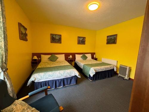 two beds in a room with yellow walls at The Stables B&B in Antrim
