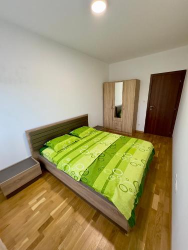 a bedroom with a large bed with a green comforter at Cozy 1 bedroom APT with free parking in Podgorica