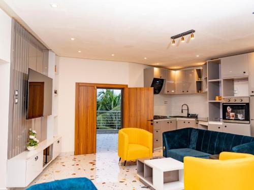 a living room with a blue couch and yellow chairs at Appartement Ibiza in Cotonou