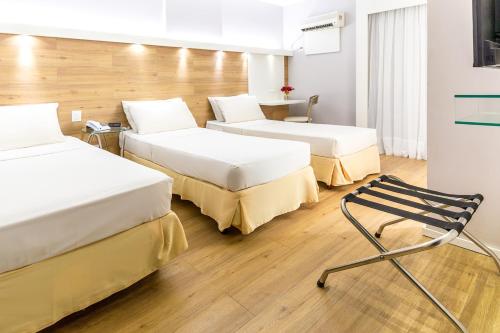 a room with two beds and a chair in it at Hotel Costamar Ponta Verde in Maceió
