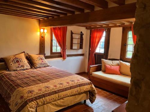 a bedroom with a bed and a couch and windows at Maison au calme a la campagne in Hermival-les-Vaux