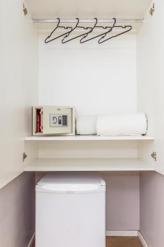 a white laundry room with a microwave on a shelf at Hotel Costamar Ponta Verde in Maceió