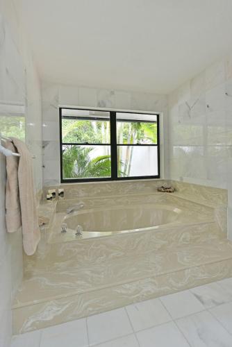 a large white bathroom with a tub and a window at Cozy home with big pool in Wellington! in Wellington