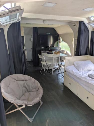 une chambre avec un lit et un bureau dans une camionnette dans l'établissement Bateau studio terrasse vue sur l'eau et nature, à Saint-Usage