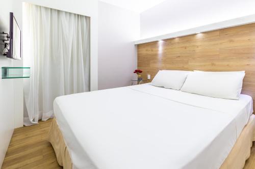 a bedroom with a large white bed with a wooden headboard at Hotel Costamar Ponta Verde in Maceió