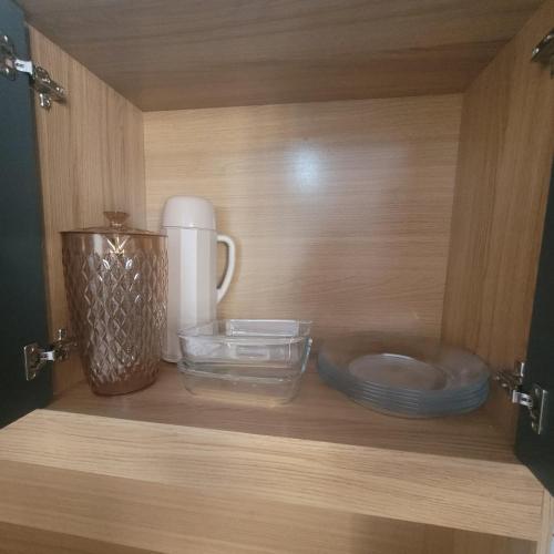 a wooden cabinet with bowls and plates on a shelf at Casa Limoeiro in Primavera do Leste