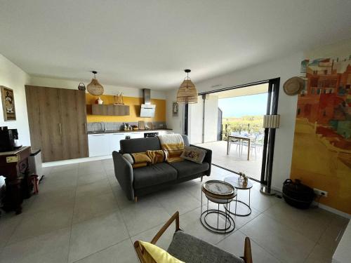 un salon avec un canapé et une cuisine dans l'établissement Appartement jardin de livia 2 rez de jardin, à Porticcio