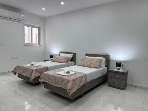 a bedroom with two beds and a window at Mediterranean Nest in Is-Swieqi