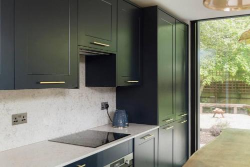 a kitchen with green cabinets and a counter top at Parea Living - Spacious North London House with Big Garden in London