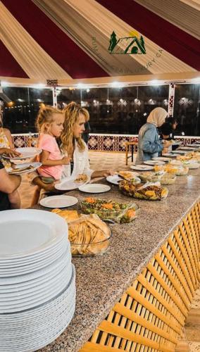 a buffet line with plates of food and people eating at Rum city Star LUXURY Camp in Wadi Rum