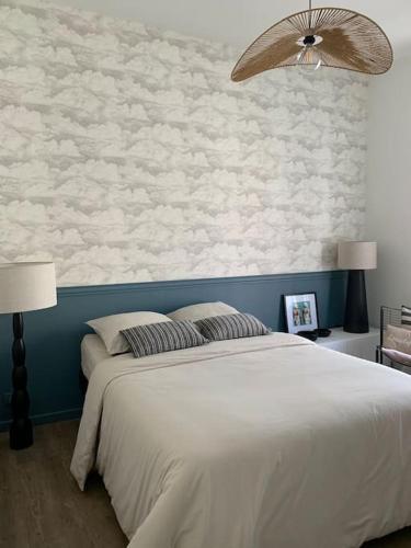 - une chambre avec un lit blanc et un mur avec des nuages dans l'établissement Retour de plage Wimereux, à Wimereux