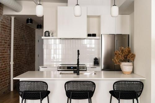 uma cozinha com armários brancos e um balcão com cadeiras em Maison Place Jacques-Cartier by Luxury In Transit em Montréal