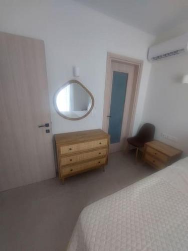 a bedroom with a bed and a dresser and a mirror at Anesis Luxury Hospitality in Karpathos Town