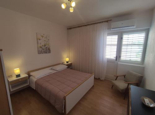 1 dormitorio con cama, silla y ventana en Apartment Landeka en Primošten