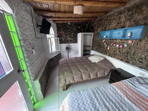 a bedroom with two beds and a stone wall at La isla surf Camp de punta hermosa in Punta Hermosa
