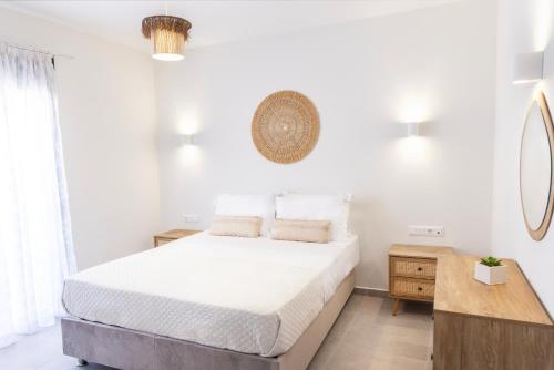 a white bedroom with a bed and a table at Anesis Luxury Hospitality in Karpathos Town