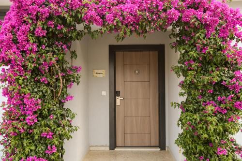 un bâtiment avec des fleurs roses autour d'une porte dans l'établissement Talia Villalari, à Fethiye