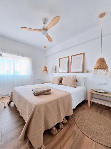 een witte slaapkamer met een groot bed en een ventilator bij Apartamento Boho Chic in Denia