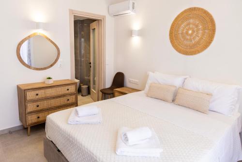 a bedroom with a large white bed with towels on it at Anesis Luxury Hospitality in Karpathos Town