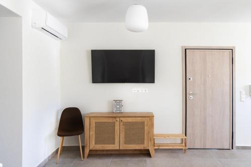 a room with a tv and a chair and a table at Anesis Luxury Hospitality in Karpathos Town