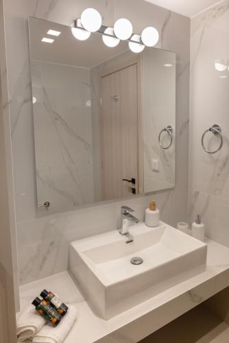 a white bathroom with a sink and a mirror at Anesis Luxury Hospitality in Karpathos Town