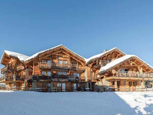 un grand bâtiment en rondins avec de la neige au sol dans l'établissement Chalet skis aux pieds avec spa et sauna, Alpe d'Huez - FR-1-645-41, à Huez