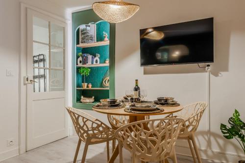 d'une salle à manger avec une table, des chaises et une télévision. dans l'établissement Hédoné by Kleidos - Bel appartement dans le centre de Château-Thierry, à Château-Thierry