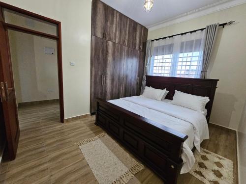 a bedroom with a large bed with a wooden headboard at Orgonite SmartHomes in Kampala