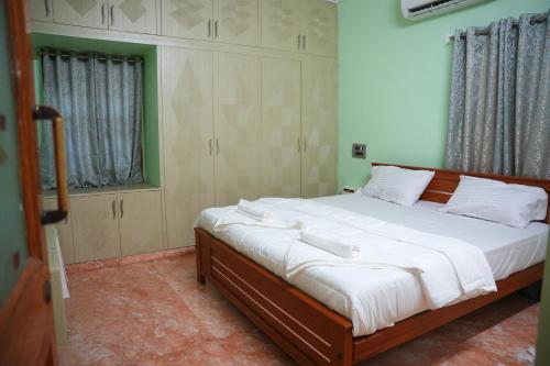 a bedroom with a large bed with white sheets at The HR STAY INN TIRUPATI - LUXURY HOMESTAY - NEAR ALIPIRI BUS STAND AND KAPILATEERTHAM - 24 HRS HOT WATER-150 MBPS SPEED FREE WIFI & ALL OTT APPS in Tirupati