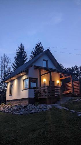 a house with lights on the side of it at Cichata - domek w Bieszczadach in Czarna