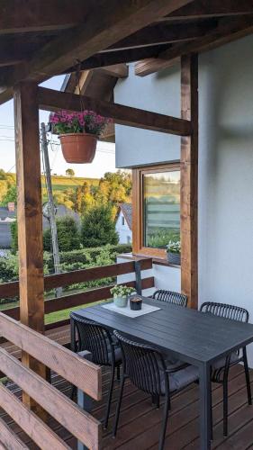 a black table and chairs on a wooden deck at Cichata - domek w Bieszczadach in Czarna