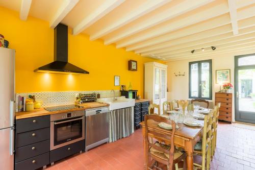 a kitchen with yellow walls and a table and chairs at Maison Les Deux Ailes, Parc arboré, billard et wifi à 1h30 de Paris in Triguères