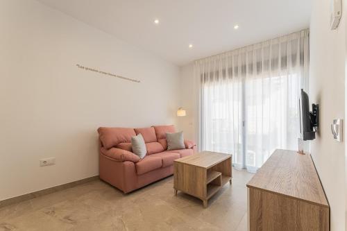 a living room with a pink couch and a table at CMDreams Platinium- Apartamentos turísticos en el centro de Mérida in Merida