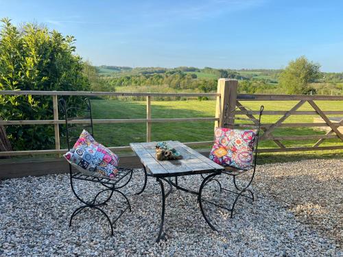 2 sillas con almohadas junto a una mesa con una valla en Quirky Barn Conversion Crowhurst Battle, en Crowhurst