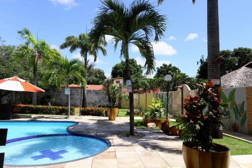 a swimming pool with palm trees and a fence at Loft Rústico com Piscina e Churrasqueira in Aquiraz