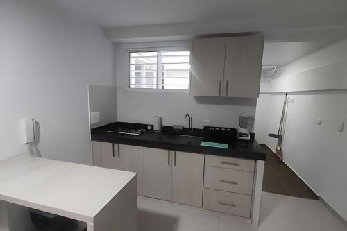a kitchen with white cabinets and a black counter top at Amplios Apartamentos San Fernando Cerca a Centros Médicos in Cali