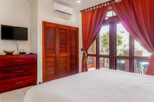 um quarto com uma cama, uma televisão e uma janela em La Paloma Blanca B1 em Jacó
