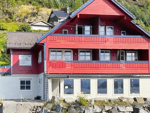 una casa roja con balcón en la parte superior. en 4 person holiday home in Selje en Selje