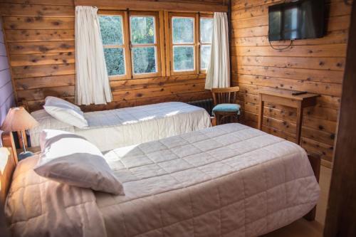 - une chambre avec 2 lits et une télévision dans l'établissement Pajaro Azul, à San Carlos de Bariloche