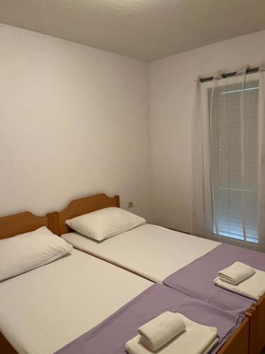 two beds in a small room with towels on them at Apartman Vučemil in Orebić