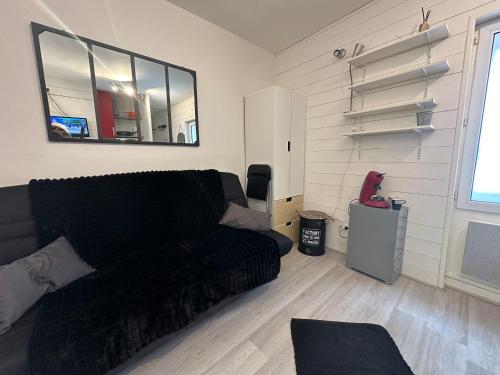 - un salon avec un canapé noir et une fenêtre dans l'établissement Charmant studio Carmes 2 - CDDT, à La Rochelle