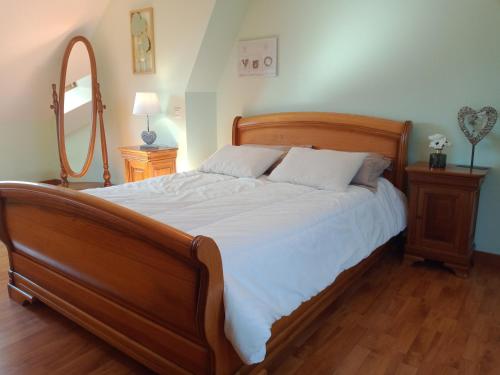 a bedroom with a large wooden bed with white sheets at GITE la belle échappée in Jullouville-les-Pins